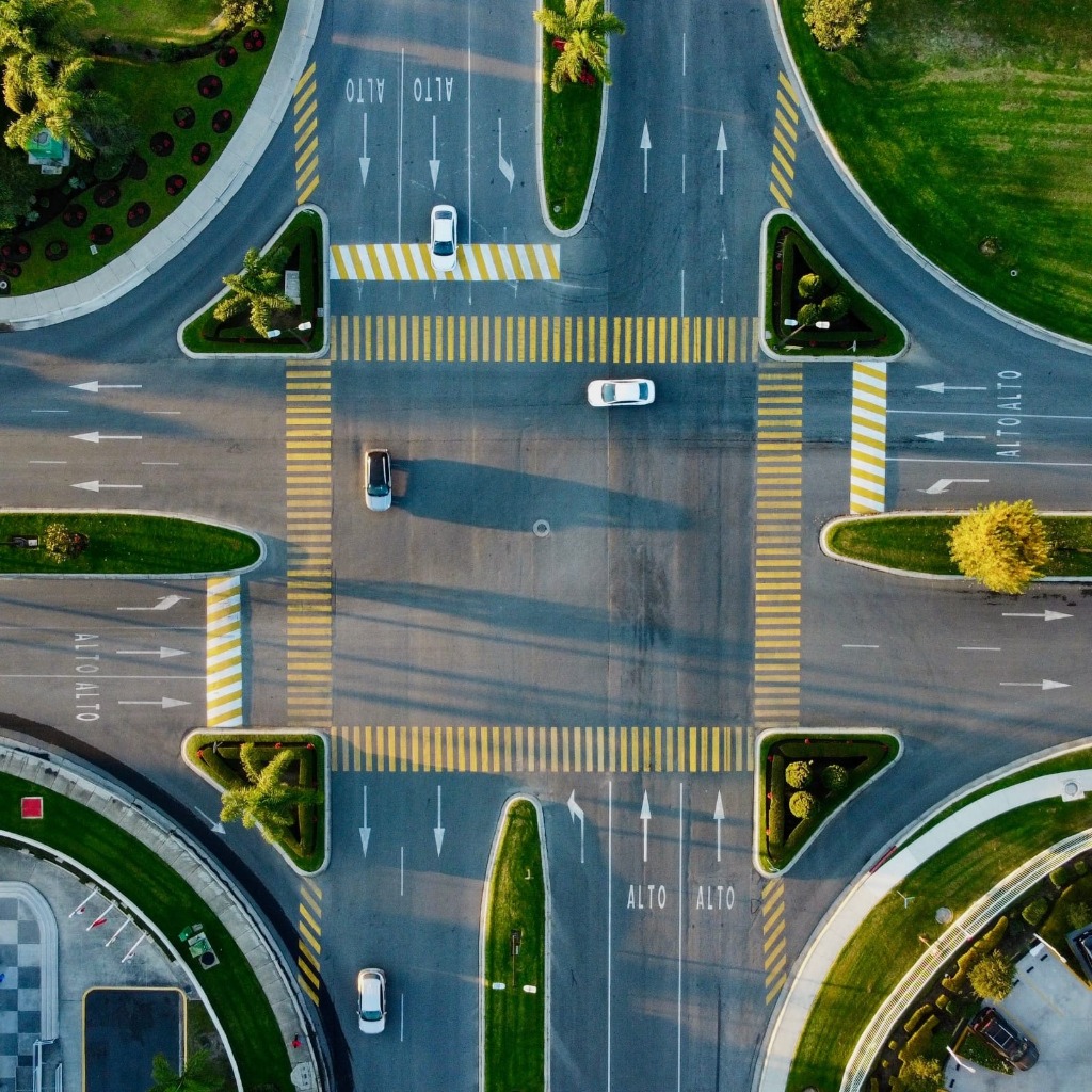 Aerial overhead view of a modern clean urban intersection with pedestrian zebra crossings and lane directional arrows