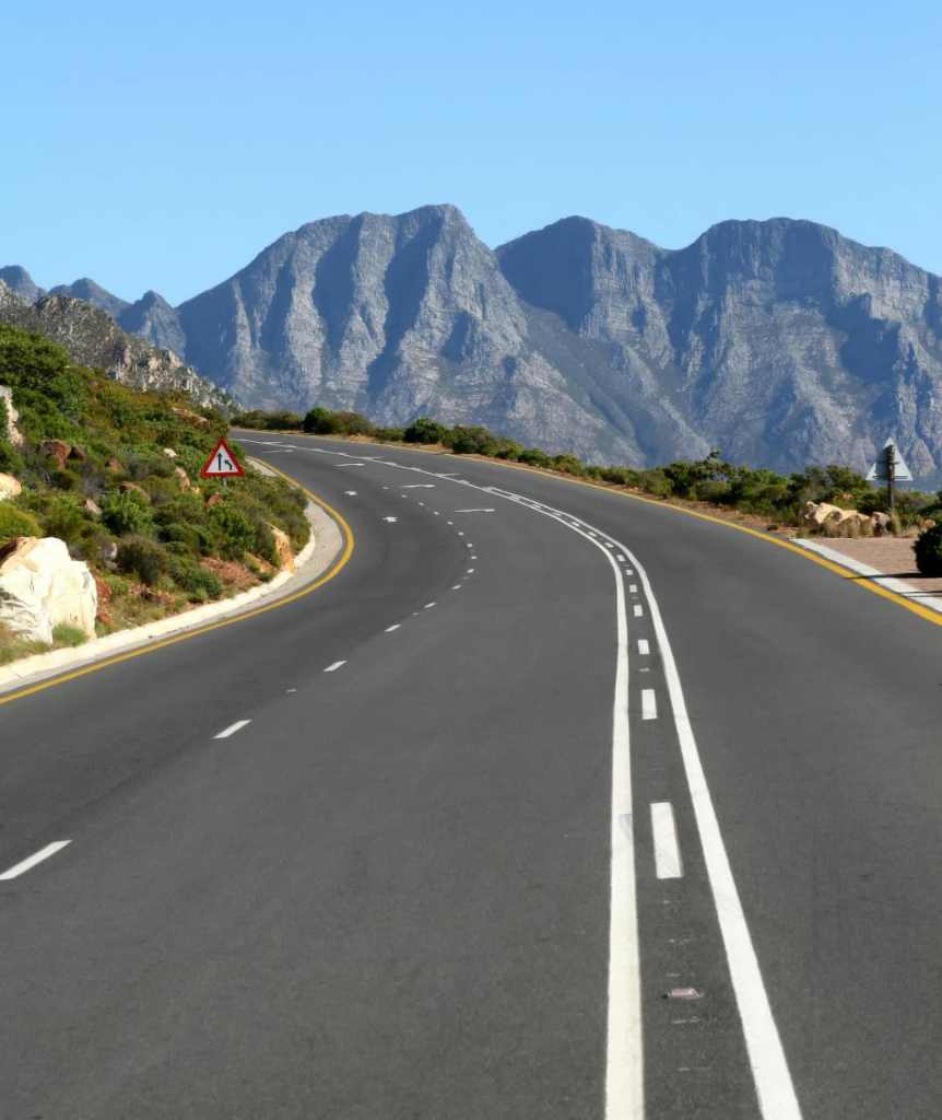 Scenic curving mountain highway showcasing high-reflectivity road lane marking lines and regulatory signage